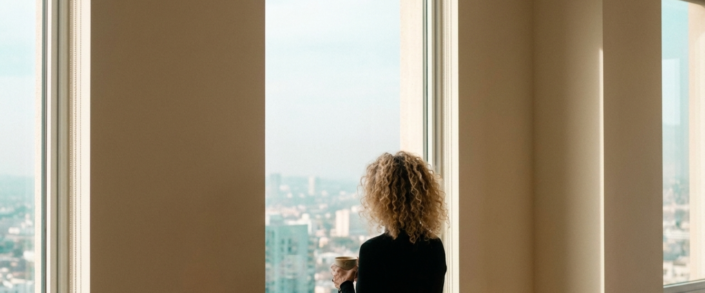 Margalit at a high window with a cup of coffee